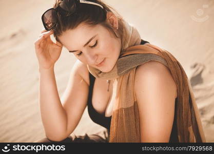 Closeup portrait of woman in sunglasses sitting on sand dune