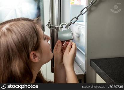 Closeup portrait of woman looking inside locked refrigerator
