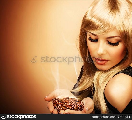 Closeup portrait of young beautiful lady holding hot roasted coffee beans, picture of attractive blonde girl enjoy coffee aroma, image of pretty elegant female isolated on brown background