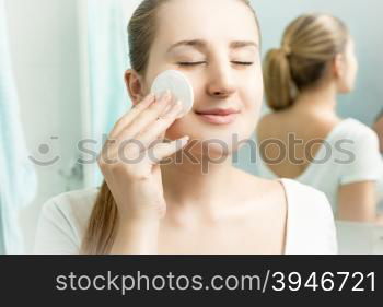 Closeup portrait of young beautiful woman cleaning skin
