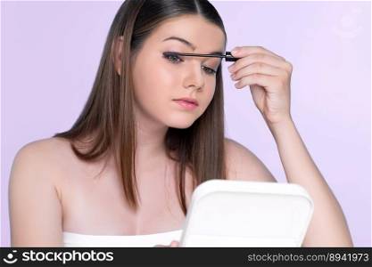 Closeup portrait of young charming applying makeup eyeshadow on her face with brush, mascara with flawless smooth skin for beauty concept.. Closeup portrait of young charming applying makeup eyeshadow with brush.