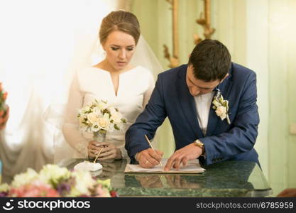 Closeup portrait of young groom signing wedding contract at registry office