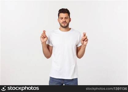 Closeup portrait of young handsome man crossing fingers, wishing, praying for miracle, hoping for the best, isolated on white background. Closeup portrait of young handsome man crossing fingers, wishing, praying for miracle, hoping for the best, isolated on white background.