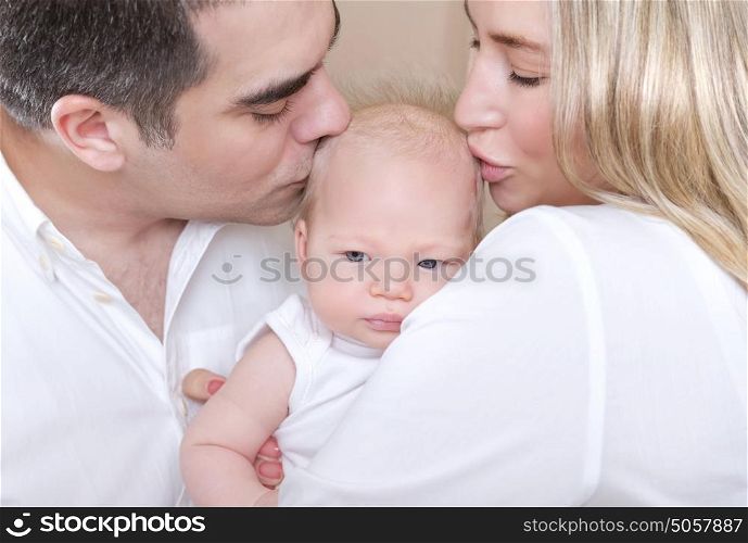 Closeup portrait of young parents kissing beautiful newborn daughter, hug with love, happy parenthood, tenderness concept