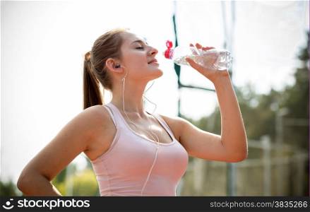 Closeup portrait of young slim woman having break at running and drinking water