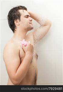Closeup portrait of young smiling man washing at shower