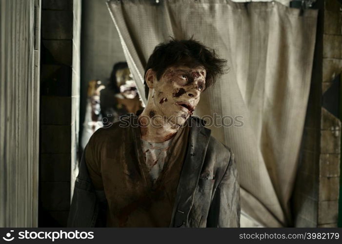 Closeup portrait of zombie killer with creepy bloody face. Ugly undead man in abandoned room. Closeup zombie killer with creepy bloody face