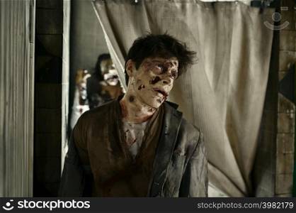 Closeup portrait of zombie killer with creepy bloody face. Ugly undead man in abandoned room. Closeup zombie killer with creepy bloody face