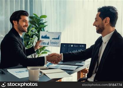 Closeup professional busi≠ssman shaking hands over desk in modern office after successfully analyzingπ≤of dashboard data paper as teamwork and∫egrity handshake in workplace concept. fervent. Closeup busi≠ssman handshake over desk with BI papers. fervent