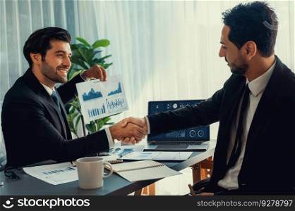 Closeup professional businessman shaking hands over desk in modern office after successfully analyzing pile of dashboard data paper as teamwork and integrity handshake in workplace concept. fervent. Closeup businessman handshake over desk with BI papers. fervent