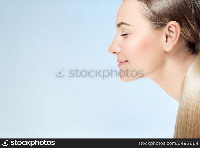 Closeup profile portrait of a nice blond girl with closed eyes isolated on blue background, conceptual photo of purity and beauty care with copy space. Beauty care concept