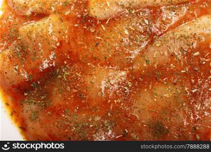 Closeup raw marinated chicken breasts with spices and herbs as background