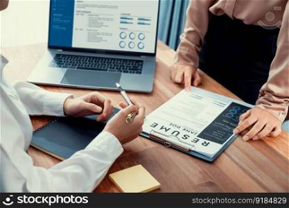 Closeup resume paper with qualifications on the desk during job interview in the office with young applicant candidates and interviewer, discussing on application of the position. Enthusiastic. Closeup resume paper with qualifications on desk during interview. Enthusiastic