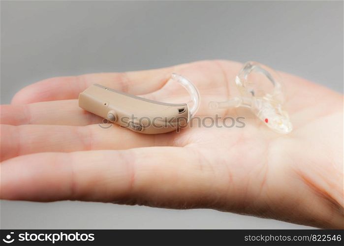 Closeup senior woman with electronic hearing aid in her hand. Health care, hear disorder, device for the deaf.. senior person holding hearing aid closeup