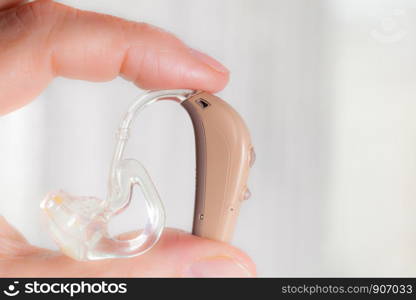 Closeup senior woman with electronic hearing aid in her hand. Health care, hear disorder, device for the deaf.. senior person holding hearing aid closeup
