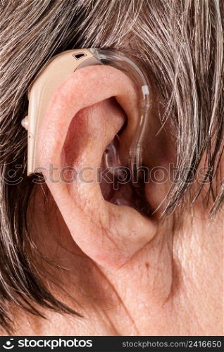 Closeup senior woman with hearing aid in her ear. Health care, hear&lify, device for the deaf.. Closeup senior woman using hearing aid