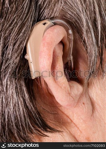Closeup senior woman with hearing aid in her ear. Health care, hear amplify, device for the deaf.. Closeup senior woman using hearing aid