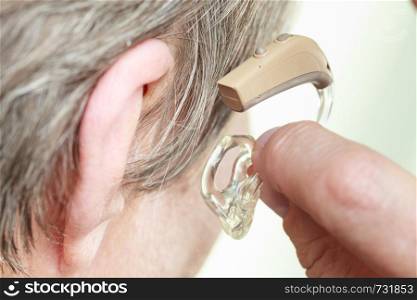Closeup senior woman with hearing aid in her ear. Health care, hear amplify, device for the deaf.. Closeup senior woman using hearing aid