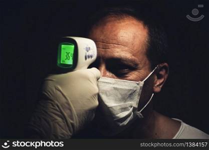 Closeup shot of a Infrared thermometer measuring a healthy senior man&rsquo;s normal body temperature for coronavirus