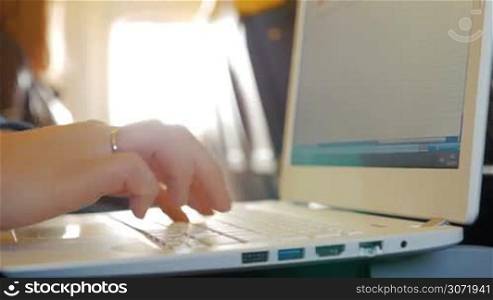 Closeup shot of a laptop keyboard and female fingers typing on it.