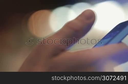 Closeup shot of a smartphone in male hand. Man is texting to friends.