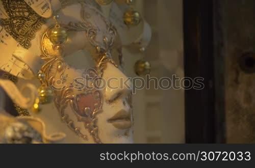 Closeup shot of a white Venetian carnival mask decorated with golden fancy pattern, little bells and musical staff.
