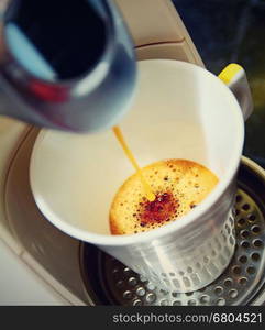 Closeup shot of an hot fresh espresso pouring to the cup in espresso machine. Photo is in retro color style.