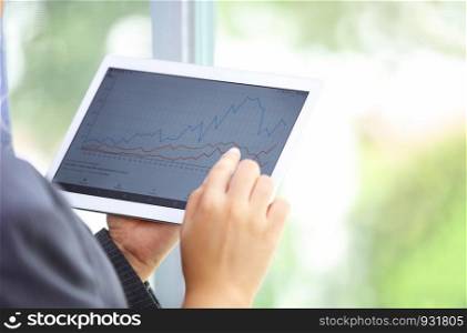 Closeup shot of an unrecognisable businesswoman analysing graphs on a digital tablet in an office