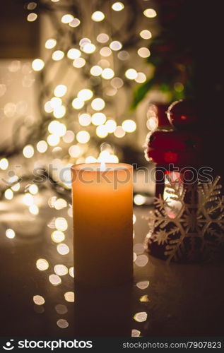 Closeup shot of burning candle against christmas lights