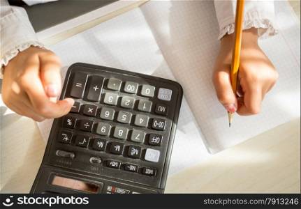 Closeup shot of child using calculator while doing homework