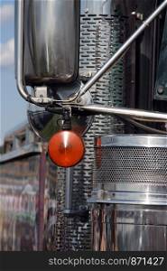 Closeup shot of chrome exhaust pipe, mirrors and other parts of a semi truck