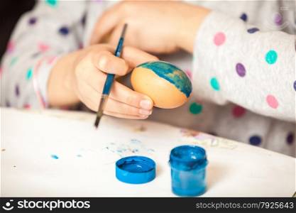 Closeup shot of girl holding brush and painting ester egg