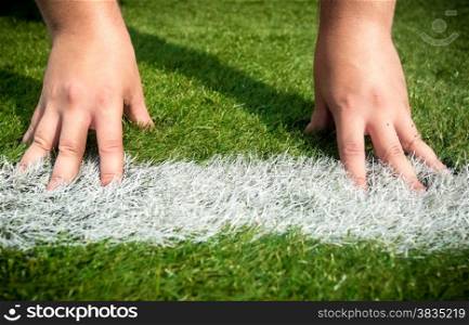 Closeup shot of hands on white start line drawn on grass