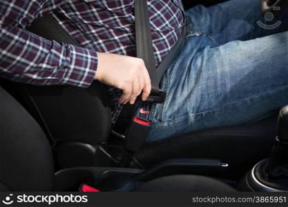 Closeup shot of male driver fastens seat belt