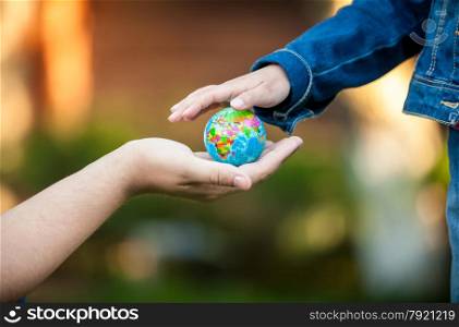 Closeup shot of man giving little girl globe on hand