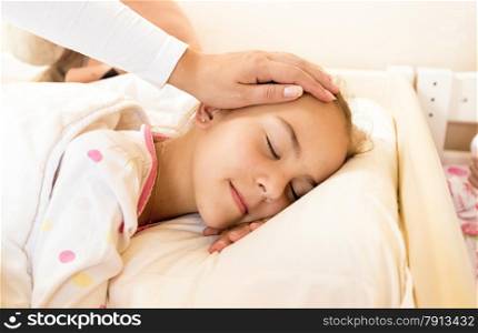 Closeup shot of mother holding hand on daughters head at bed