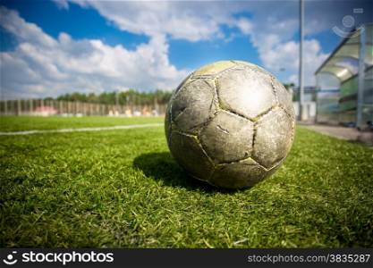Closeup shot of old soccer ball on grass field at sunny day