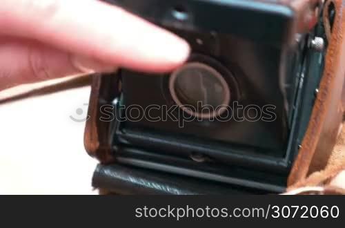 Closeup shot of opening a lens cap on vintage medium format camera before taking a shot. Wall of old building is reflecting in focussing screen.