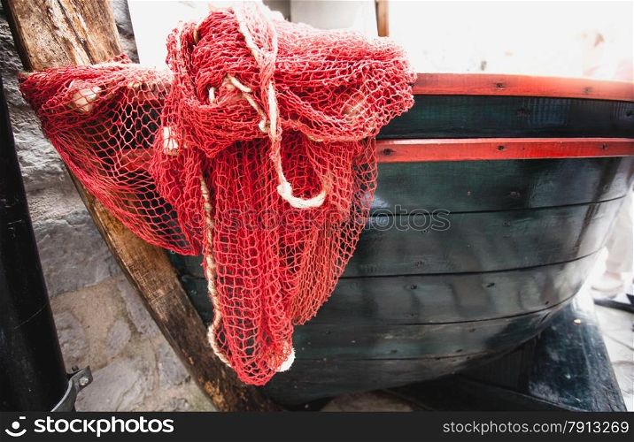 Closeup shot of red fishnet lying blue wooden rowboat