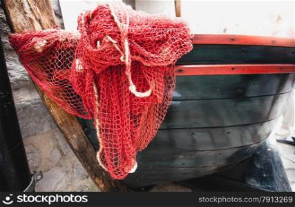 Closeup shot of red fishnet lying blue wooden rowboat