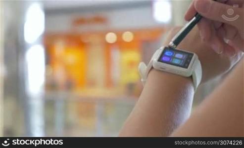 Closeup shot of smart watch on wrist of female user, she is touching the screen with stylus.