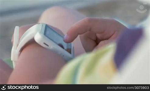 Closeup shot of smart watch with white strap on a hand of child.