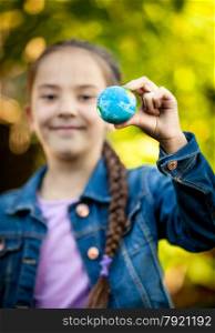 Closeup shot of smiling girl holding little Earth at hand