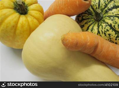 closeup shot of squashes and carrots against a light background