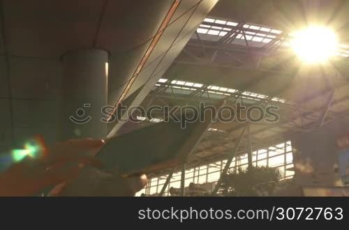 Closeup shot of tablet PC in female hands. Shot is made in some modern building, sun is shining through the roof.