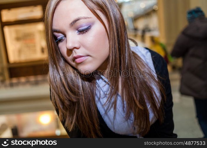 Closeup shot of the Female looking down with blank expression on the face. Photo of young beautiful lady inside the big mall