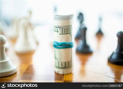 Closeup shot of twisted dollars lying on wooden chess board