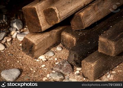 Closeup shot of wet old wooden boards on sand beach with shells and stones