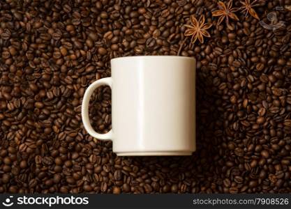 Closeup shot of white mug against coffee beans with anise stars lying like steam