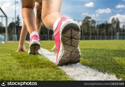 Closeup shot of woman in sneakers standing on white line drawn on grass